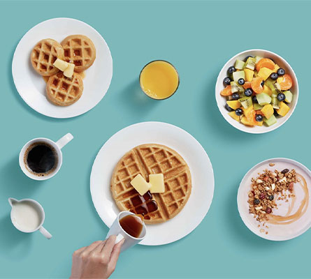 Table of breakfast items with hand pouring syrup